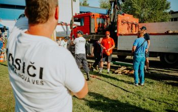 A group of firefighters in a park setting during a public demonstration near a fire truck.