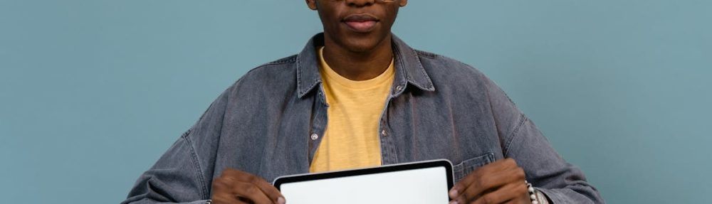 A young African American man holding a tablet displaying the word 'MOTIVATION' against a blue background.